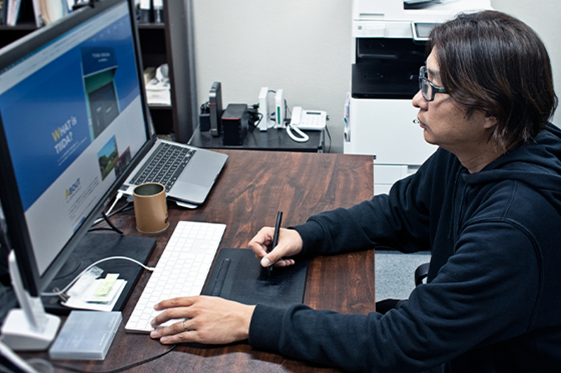 ティーダデザイン代表 村上琢也がパソコンに向かってデザイン作業をしている様子の写真